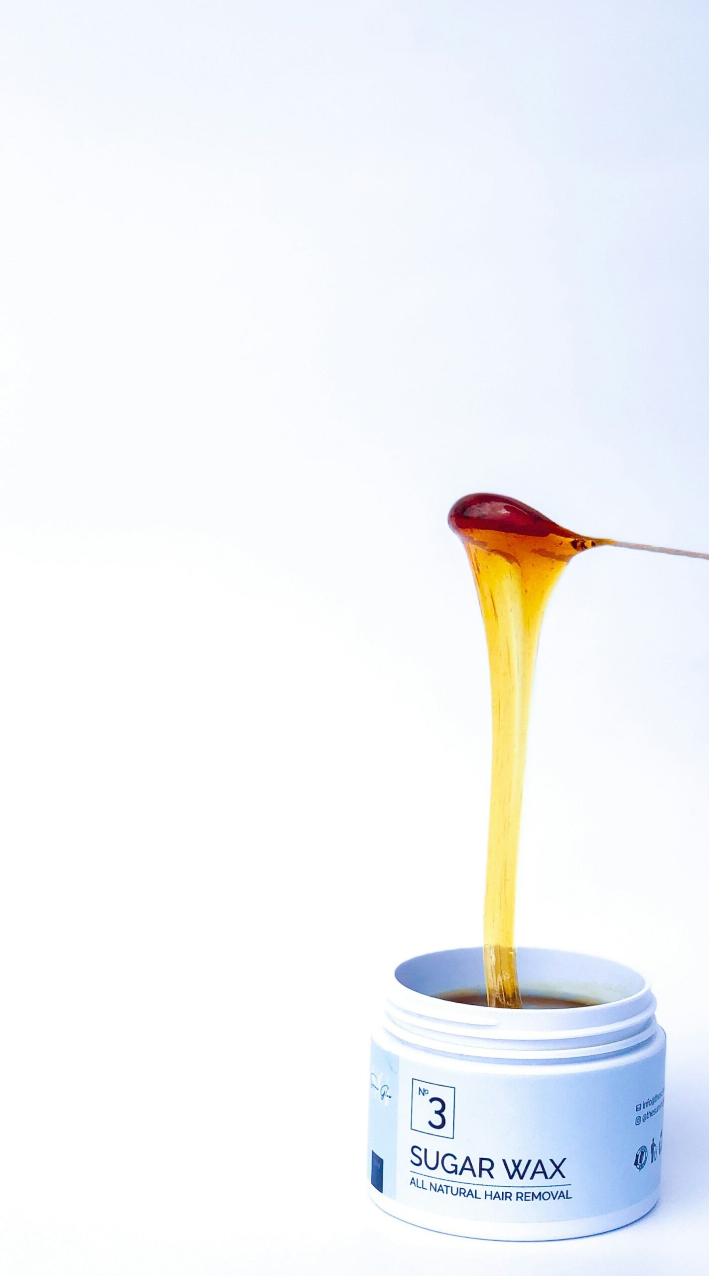 Warm wax dripping from a spatula into a jar